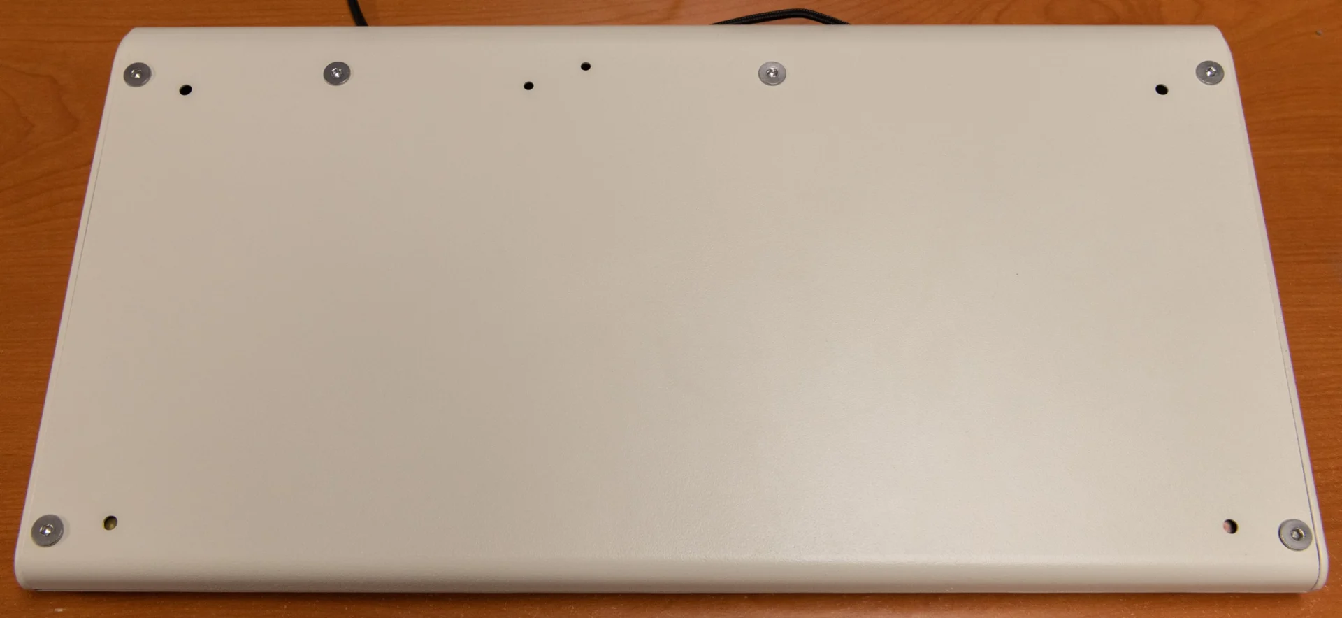 Here’s a photo of the bottom case part, as installed on a Classic M Style case FSSK. Please note that these photos are of prototypes whose case bottoms were rejected because the screws were improperly recessed and the bottom did not properly align with the contours of the case top (the bolts should be fully recessed and flush with the case bottom and the case bottom should not extend beyond the contours of the case top, and the parts should line up in the front and back though they do not in the sample). The tops had other QC issues as noted in a prior post (casting defects, mold lines, improperly drilled holes for the screws, etc.). The pair of adjacent holes on the bottom are for mounting a solenoid, which can now be done directly and the L bracket mount is no longer needed. These holes should have been recessed so the screws do not stick out of the bottom. The P clip and solenoid driver have individual, dedicated mounting posts inside the keyboard, on the case top.